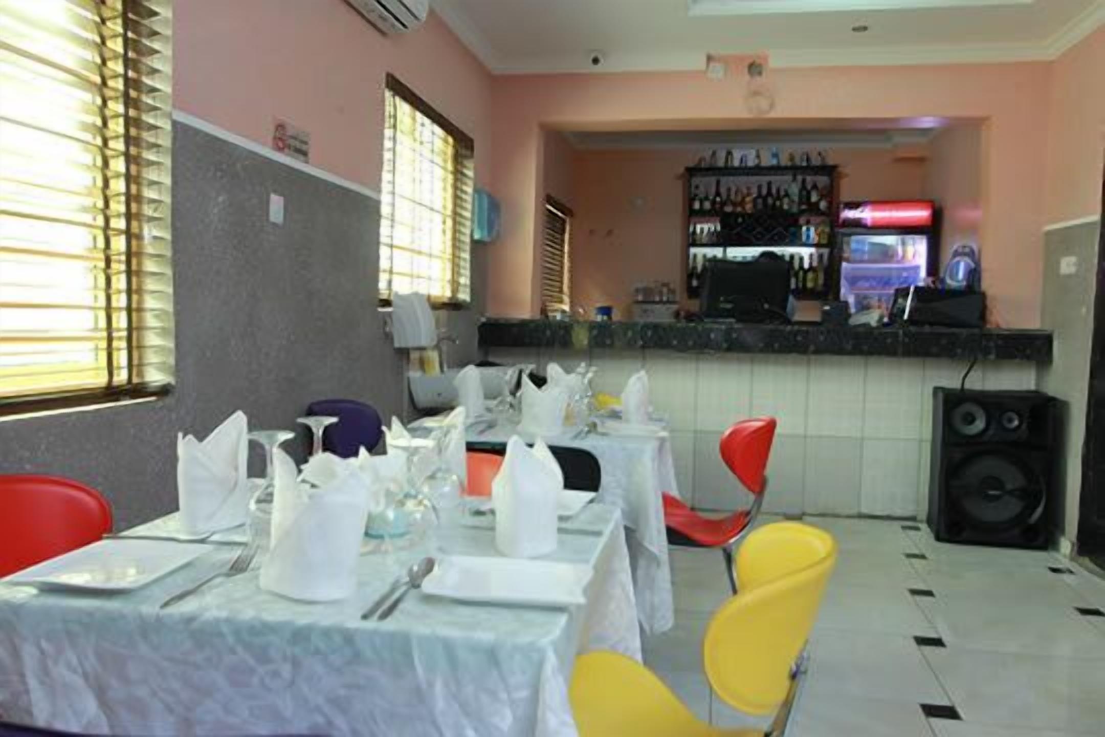 A dining area with tables set for a meal, a bar with various bottles, and a refrigerator.