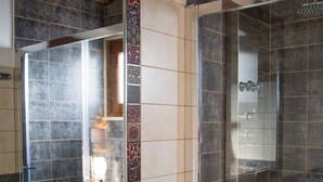 Un baño con un lavamanos de mosaico azul, una ducha con mampara de vidrio y azulejos estampados.