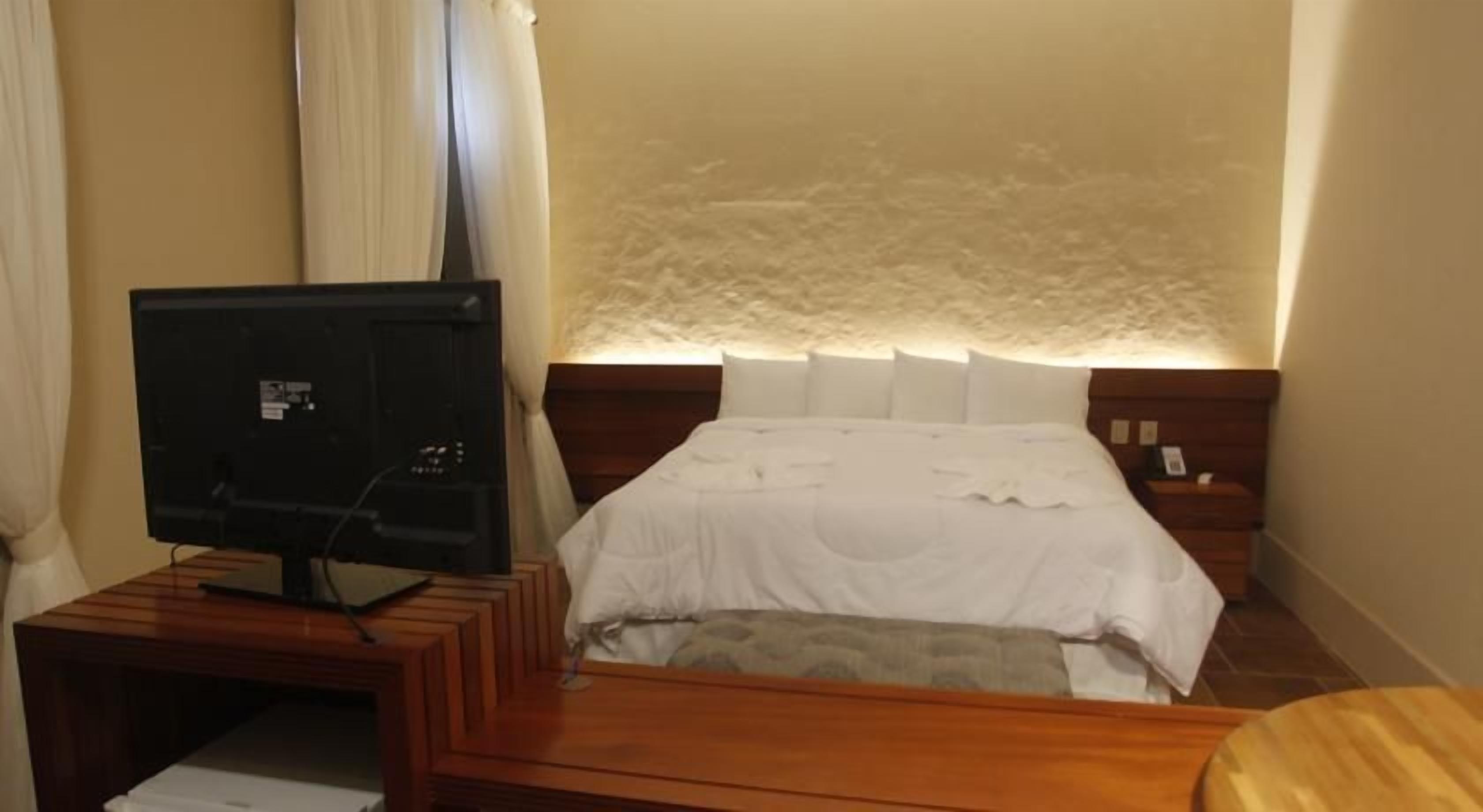 Una habitación de hotel con una cama, una mesita de noche, un televisor y una mesilla.