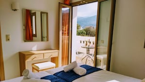 A hotel room with a bed, a wooden dresser, a mirror, and a balcony with a table and chairs. - Casa Malena (Hersonissos)
