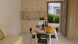A compact kitchen with wooden cabinets, a dining table with chairs, and a small dining area. - Casa Malena (Hersonissos)