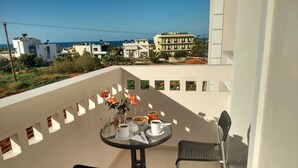 A balcony with a table set for two, featuring a vase of flowers, a bowl of cereal, and a cup of coffee. - Casa Malena (Hersonissos)