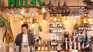 Un espace bar avec un assortiment de bouteilles et de verres, une enseigne indiquant « HÔTEL » et un panneau interdisant de fumer.