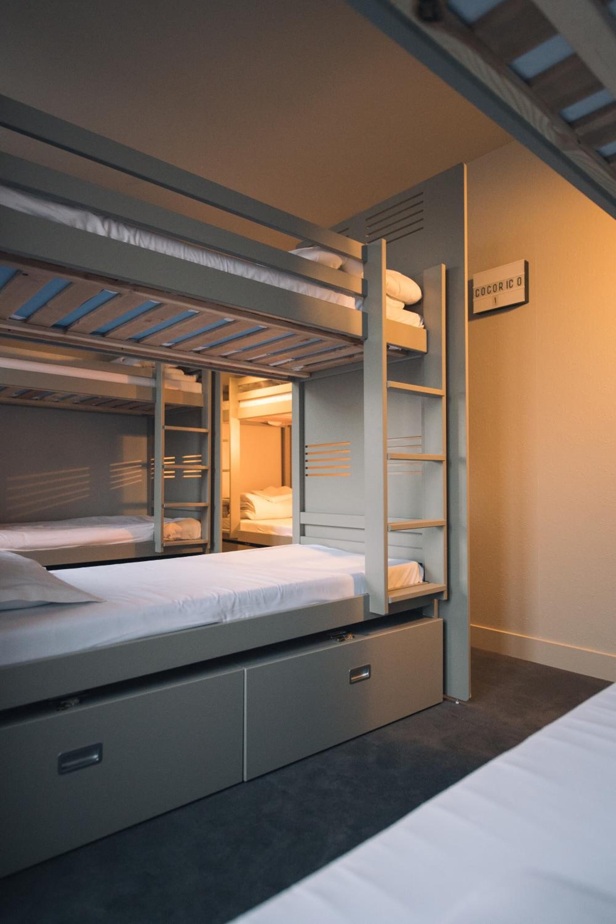 A bunk bed room with a ladder, a small desk, and a nightstand.