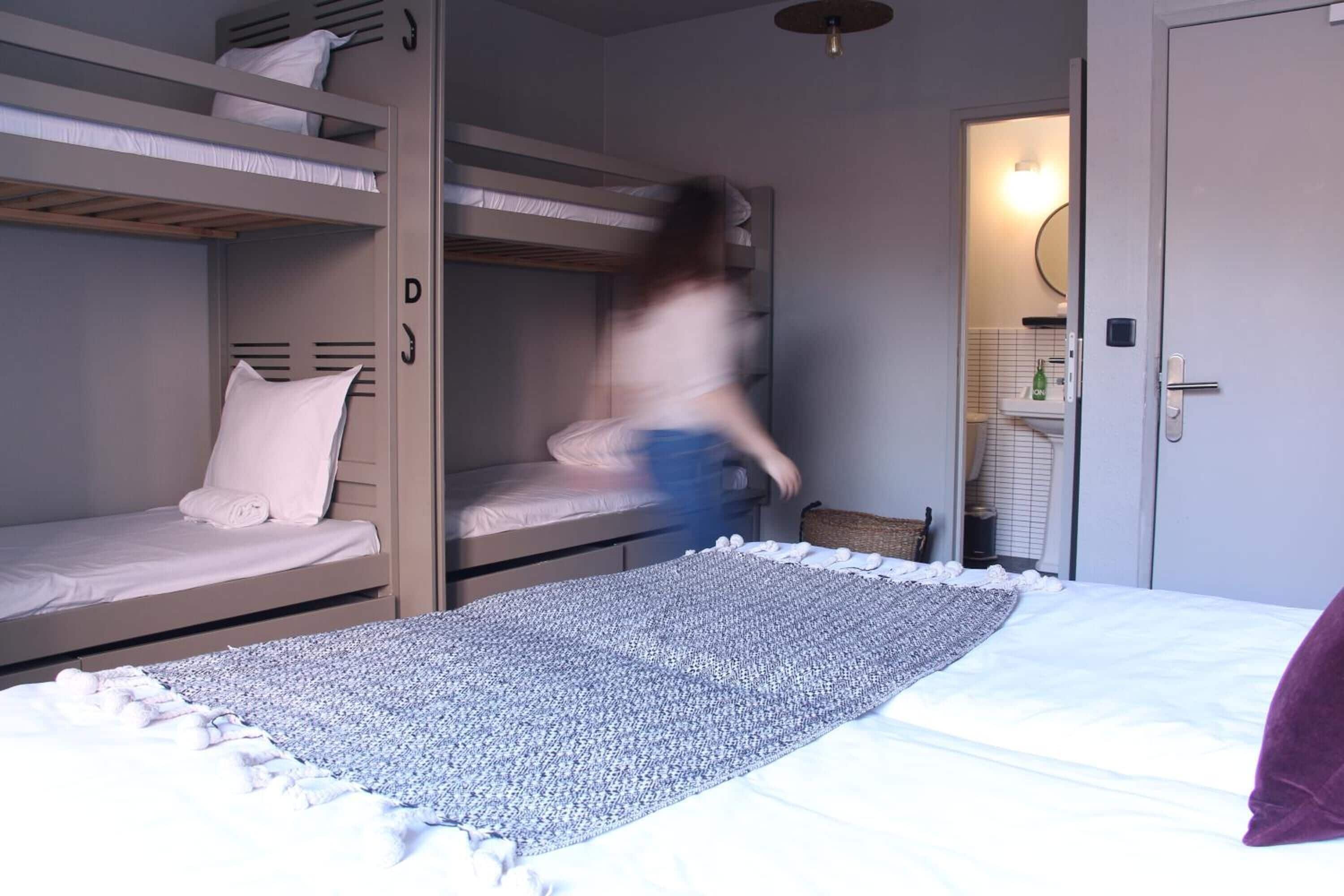 Habitación con literas, una cama individual, una mesita y un espejo.
