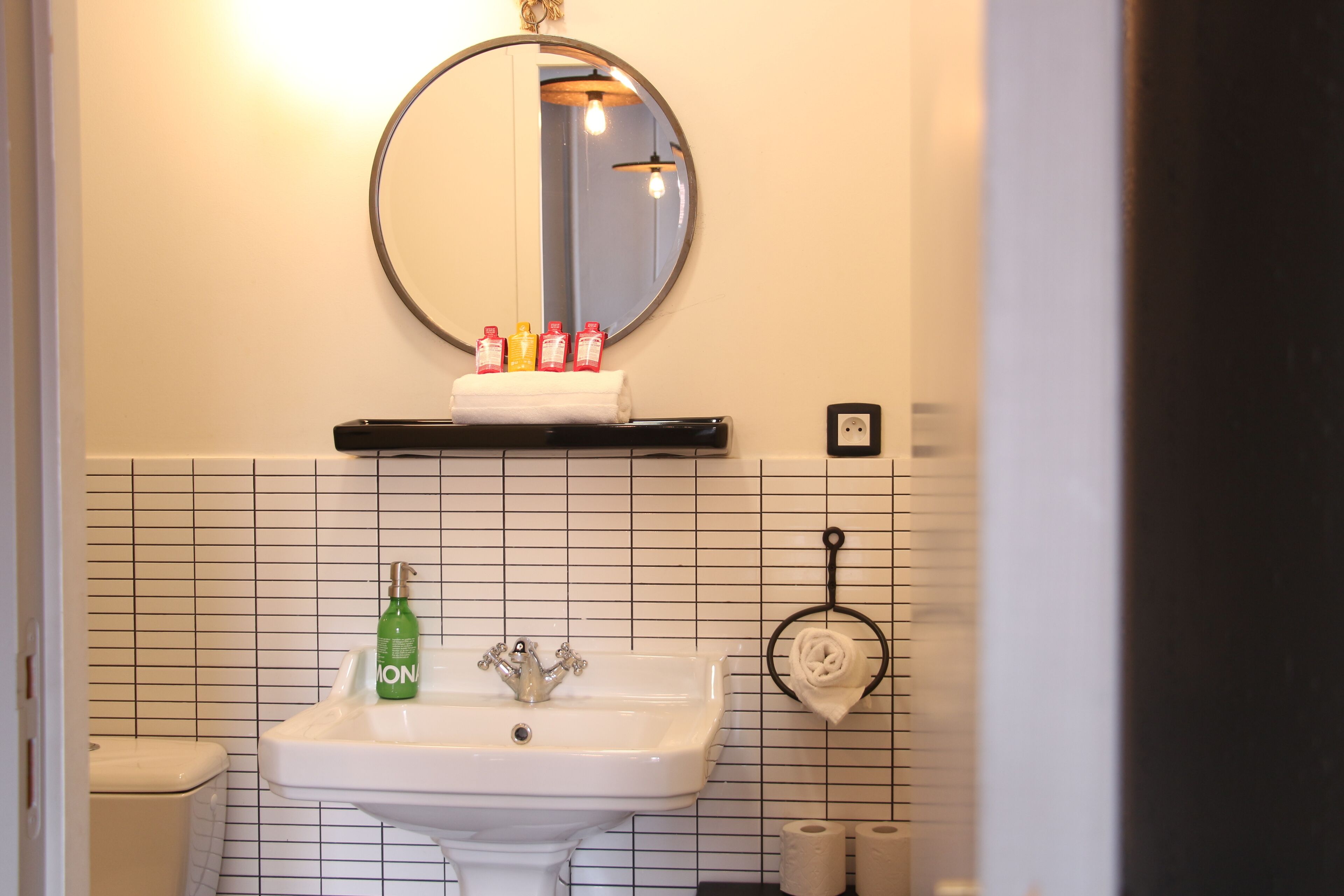 Een badkamer met een wit wastafel, een spiegel en een handdoekhouder.