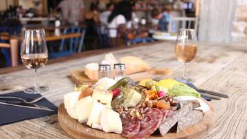 Una tabla de fiambres con diversos quesos, carnes y frutas sobre una mesa de madera en un restaurante.