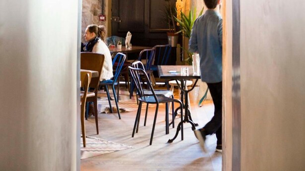 Un intérieur agrémenté d’une arche rustique qui mène à un espace repas avec des tables et des chaises.