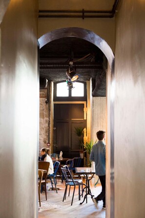 An interior with a rustic archway leading to a dining area with tables and chairs. - Ho36 hostels (Lyon)