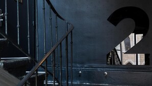 Un escalier avec des rampes et des marches noires, menant à un palier où est affiché un grand chiffre « 2 » sur le mur.