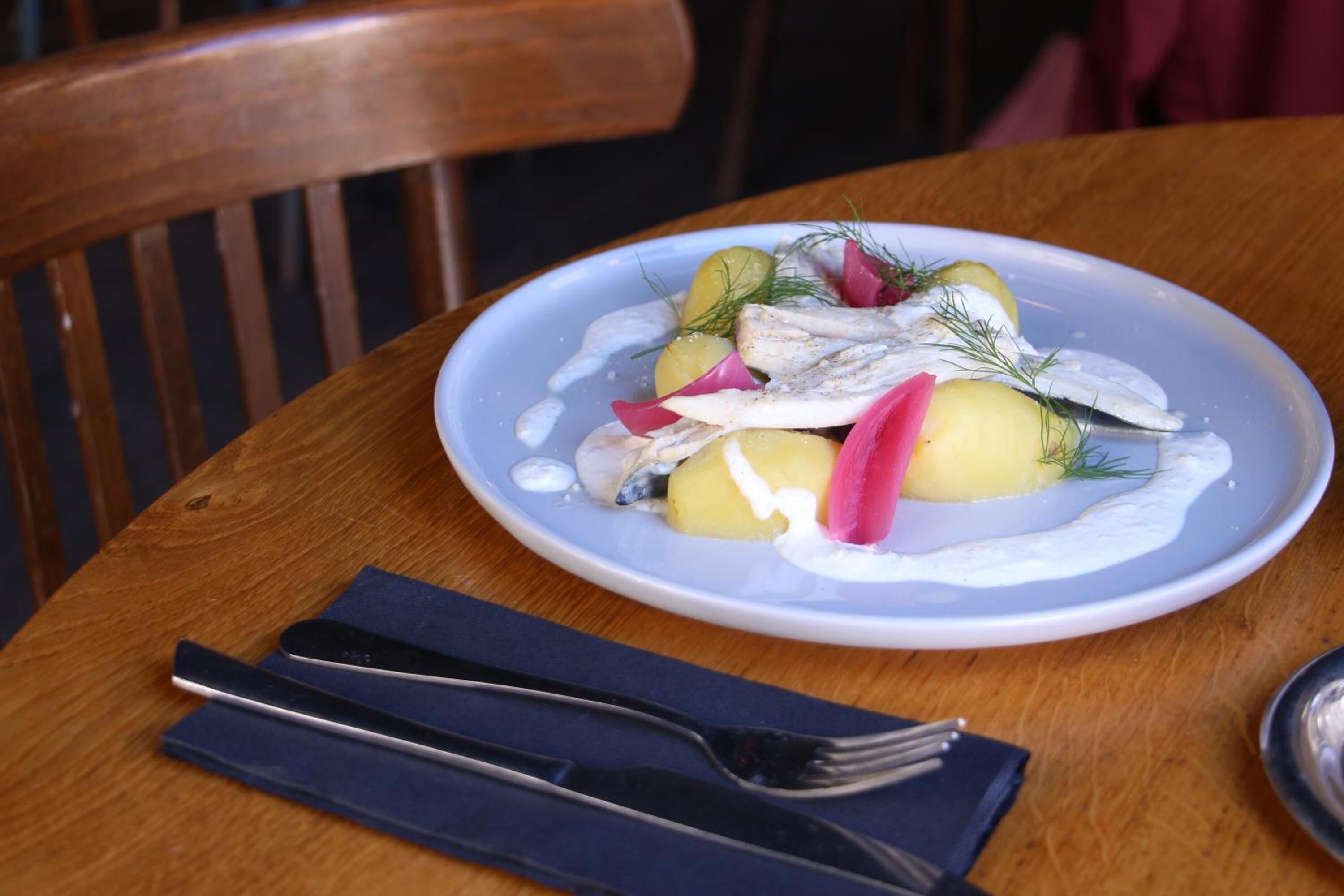 A plate of food on a wooden table with a fork and napkin beside it.