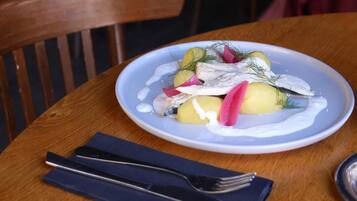 A plate of food on a wooden table with a fork and napkin beside it.