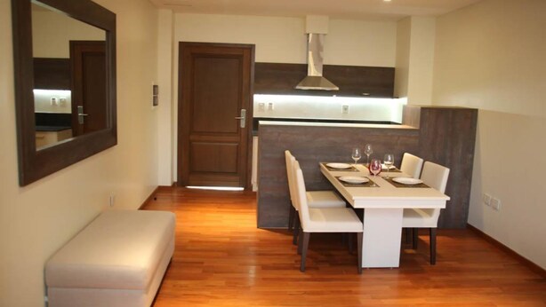 A modern kitchen with a dining area, wooden flooring, and a bench. - Andares Del Agua (Villa Elisa)