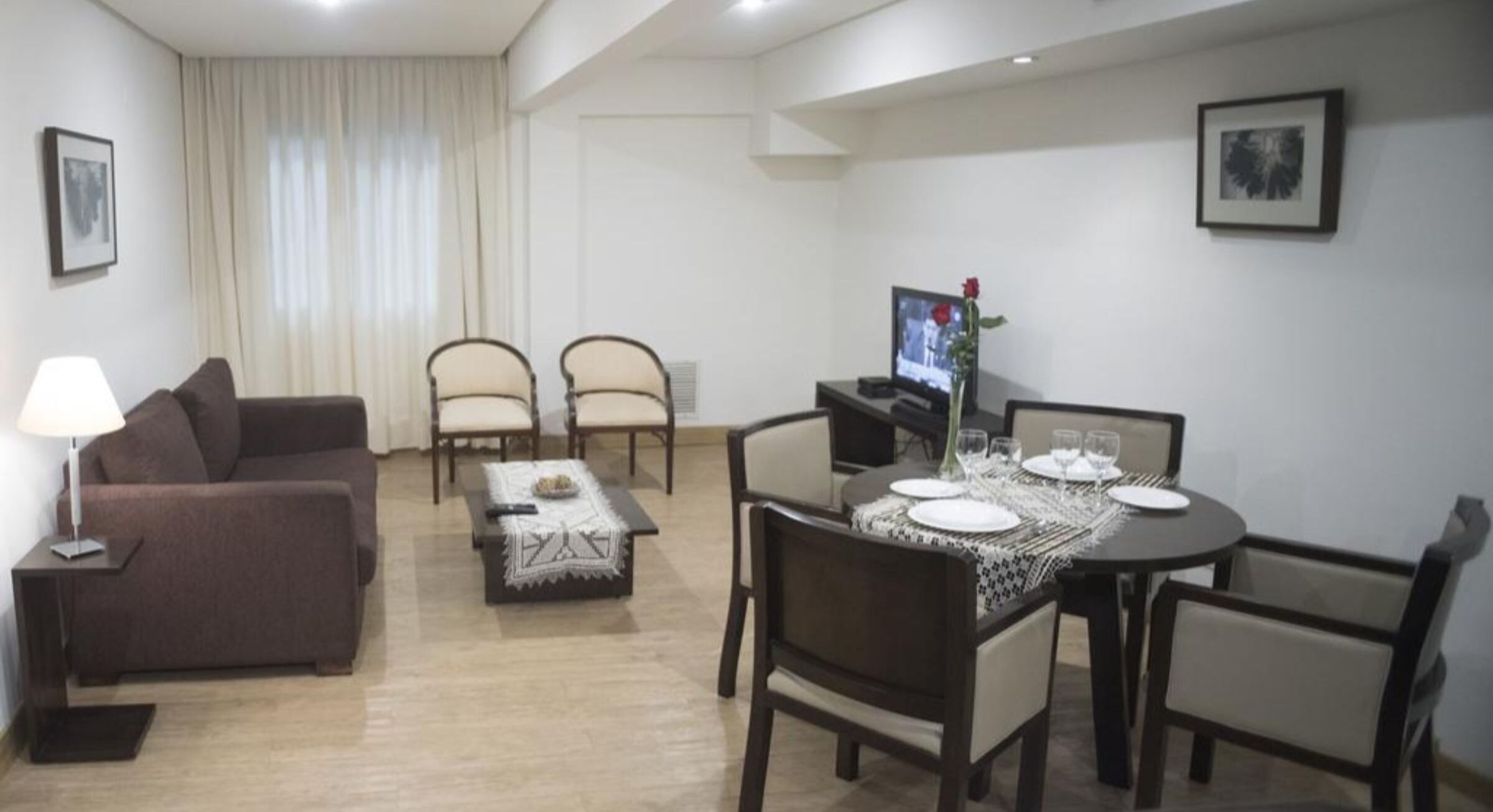 A living room with a sofa, two armchairs, a coffee table, and a dining table set for four.