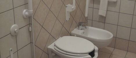 A bathroom with a toilet, bidet, and a small sink.