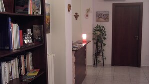 A room with a bookshelf, a desk with a lit candle, a radiator, a wall-mounted air conditioner, and a door. - Etna Inn (Motta Sant'Anastasia)