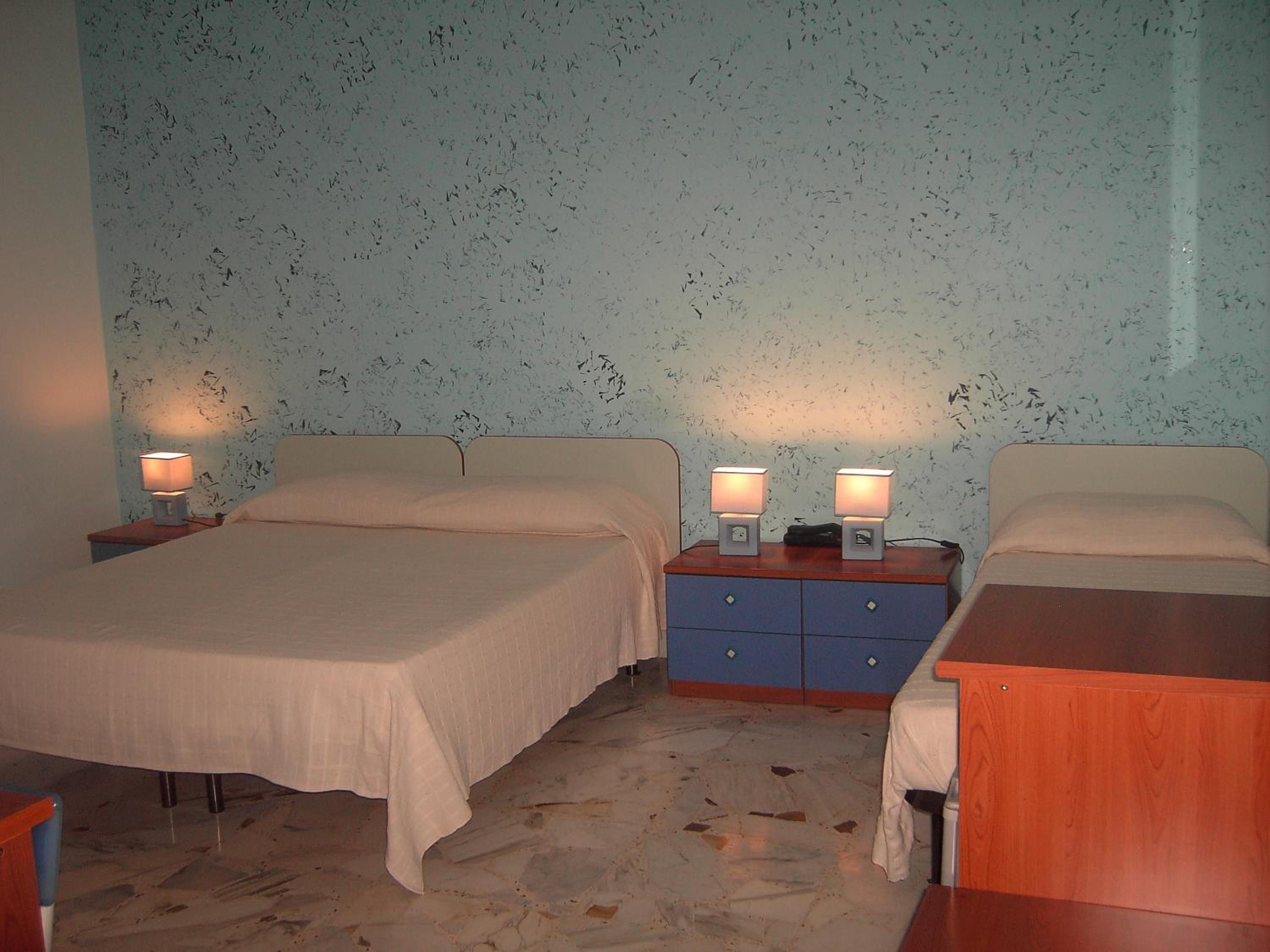 A bedroom with two beds, a nightstand with lamps, and a blue dresser.