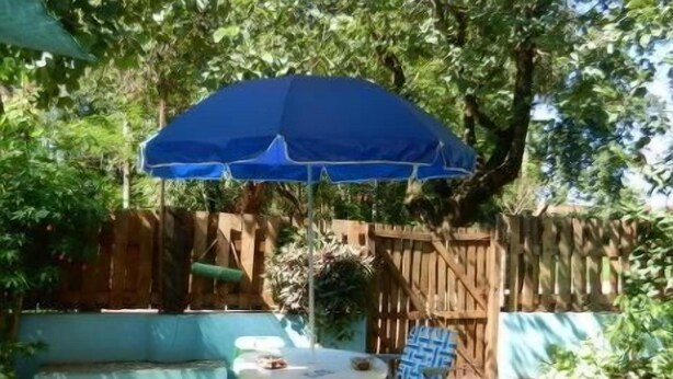 Eine Terrasse mit einem blauen Sonnenschirm, einem weißen Tisch und zwei Stühlen.