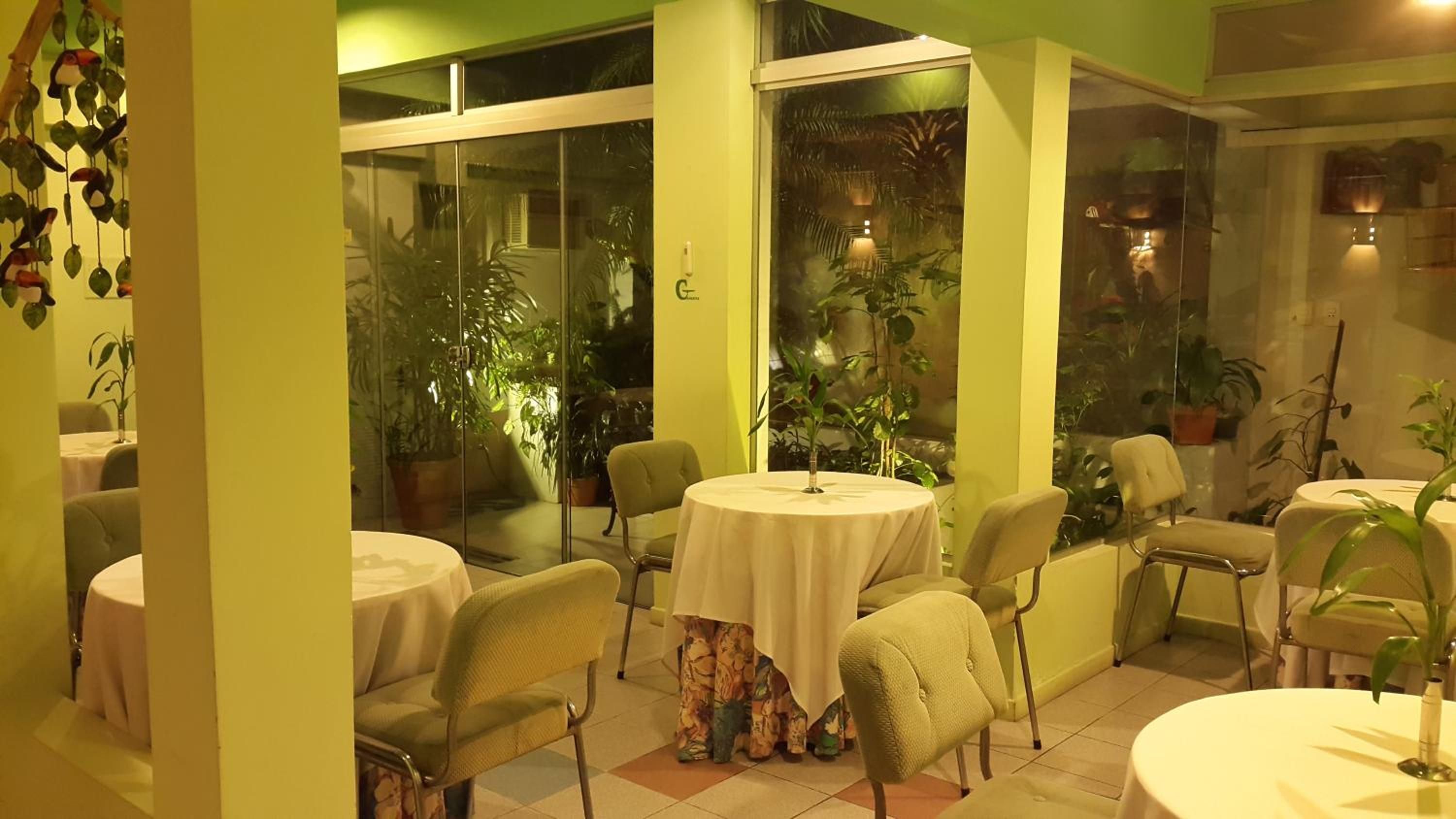 A dining area with round tables, chairs, and potted plants.