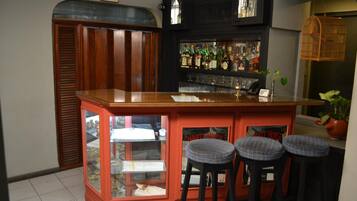 Un espace bar avec des tabourets, une vitrine et une étagère où sont exposées des bouteilles.
