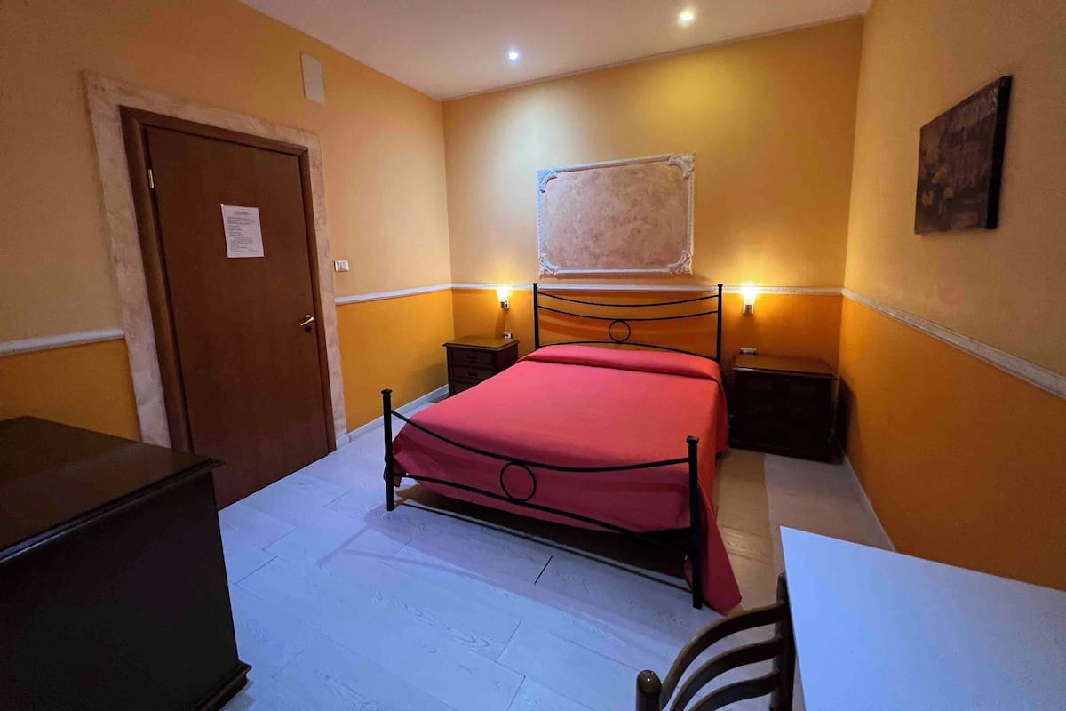 Une chambre à coucher comprenant un lit, des tables de chevet, un bureau et une armoire.