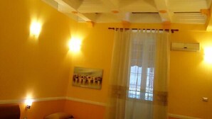 A hotel room with a bed, a small table, a chair, and a window with curtains.