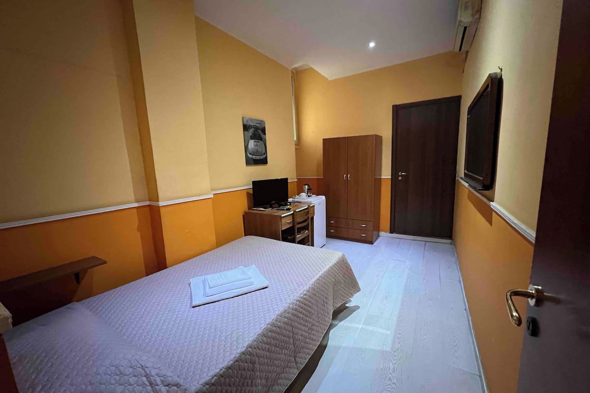 Une chambre à coucher avec un lit, un bureau, une armoire et un téléviseur.