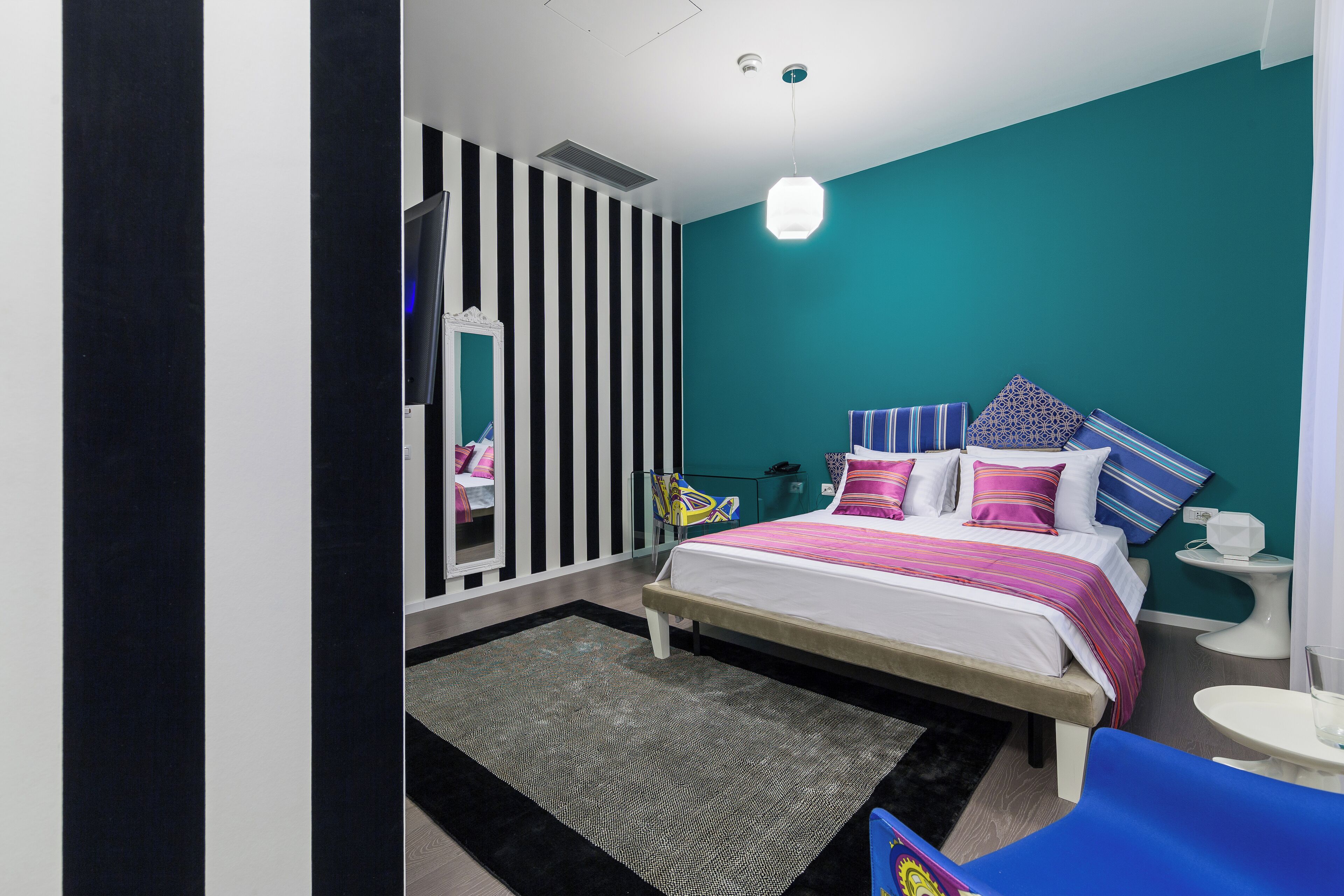 A modern bedroom with a bed, bedside table, and a mirror.