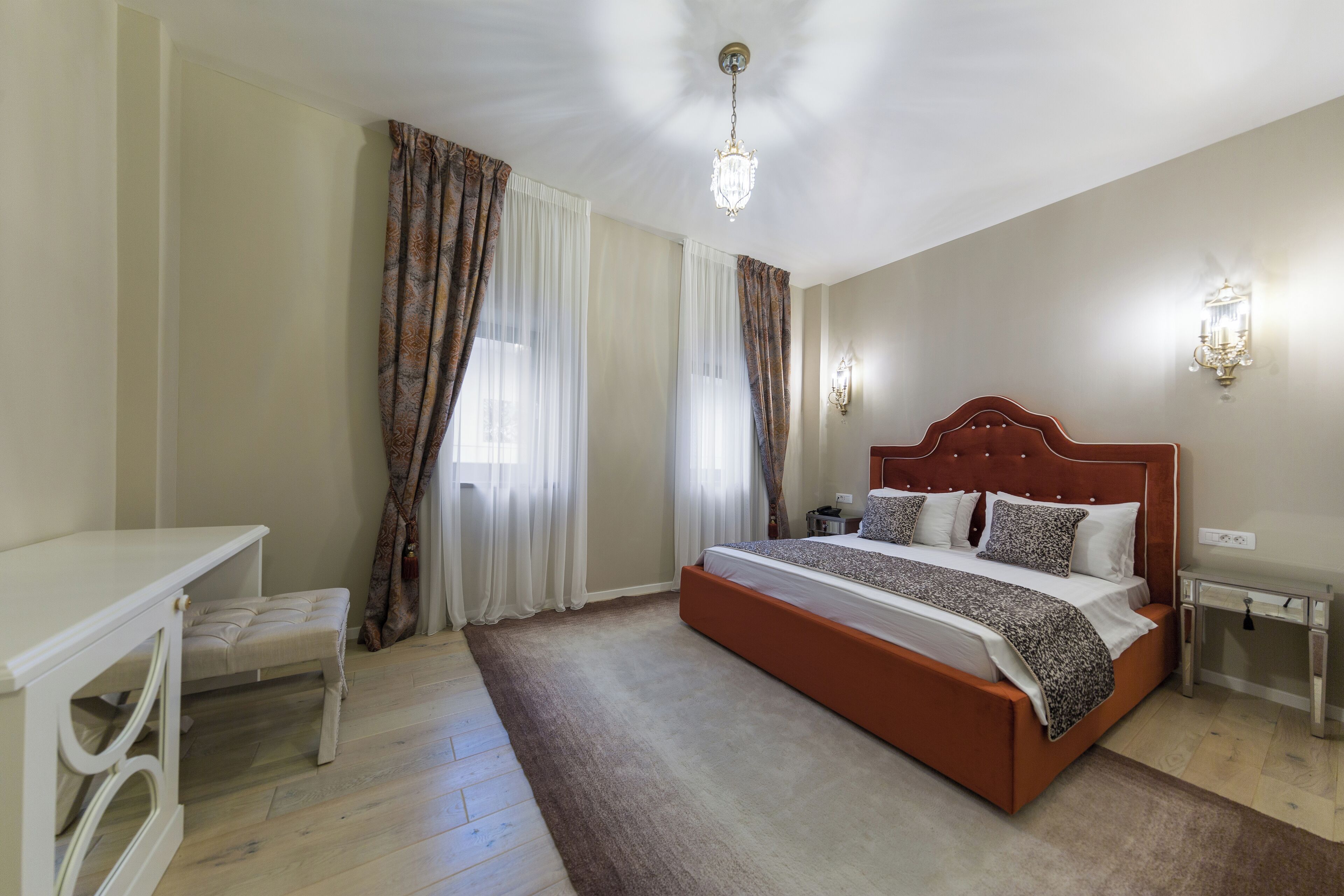 A bedroom with a large bed, a bedside table, a nightstand, and a window with curtains.
