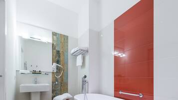 Een moderne badkamer met een witte wastafel, een spiegel, een douche met handdouche en een rode accentmuur.