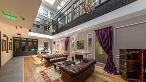 A spacious living area with a high ceiling, a fireplace, and a large window. - The Mansion Boutique Hotel (Bucharest)