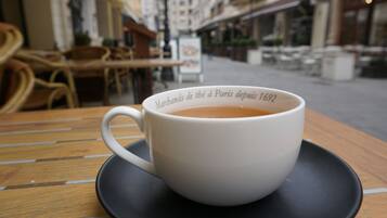 A white cup of coffee on a black saucer with a table.