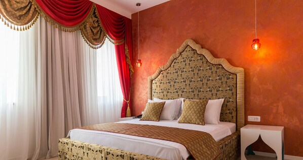 Une chambre d’hôtel avec un grand lit, des rideaux rouges et une tête de lit à motifs.