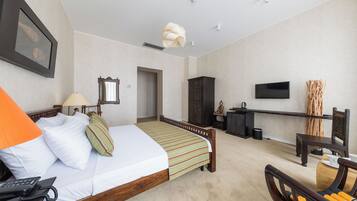 Habitación de hotel con cama, escritorio, silla, televisor y puerta del baño.