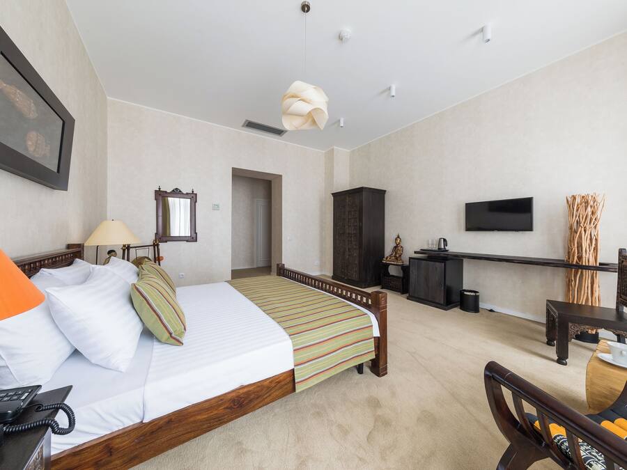 Habitación de hotel con cama, escritorio, silla, televisor y puerta del baño.