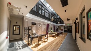 A spacious interior with a wooden floor, a mezzanine level, and a view of the sky through large windows. - The Mansion Boutique Hotel (Bucharest)
