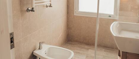Un baño moderno con inodoro, bidé y zona de ducha.