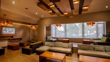 Un moderno vestíbulo de hotel con techo de madera, ventanas amplias y varias zonas de estar.