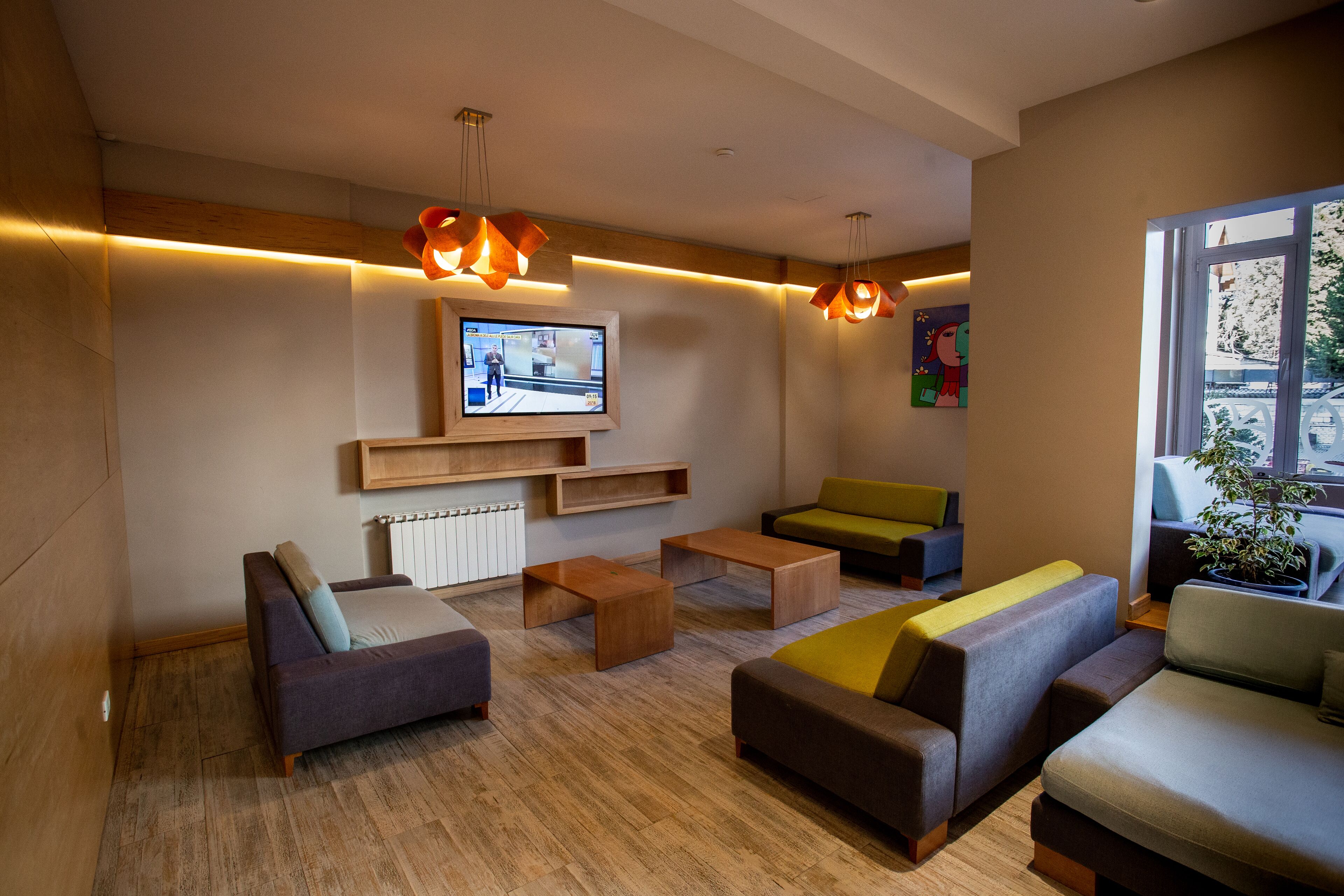 A modern lounge area with sofas, a TV, and wooden flooring.