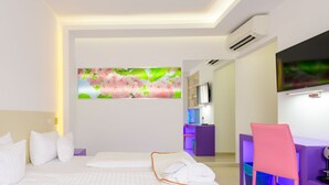 Ein modernes Hotelzimmer mit einem großen Bett, einem Schreibtisch mit Stuhl, einem Fernseher und einer Wand-Klimaanlage.