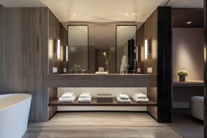 A modern bathroom with a large mirror, a bathtub, and neatly arranged towels on shelves.
