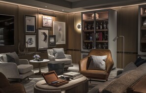 A modern living room with a leather armchair, a round coffee table, and a bookshelf filled with books and decorative items.