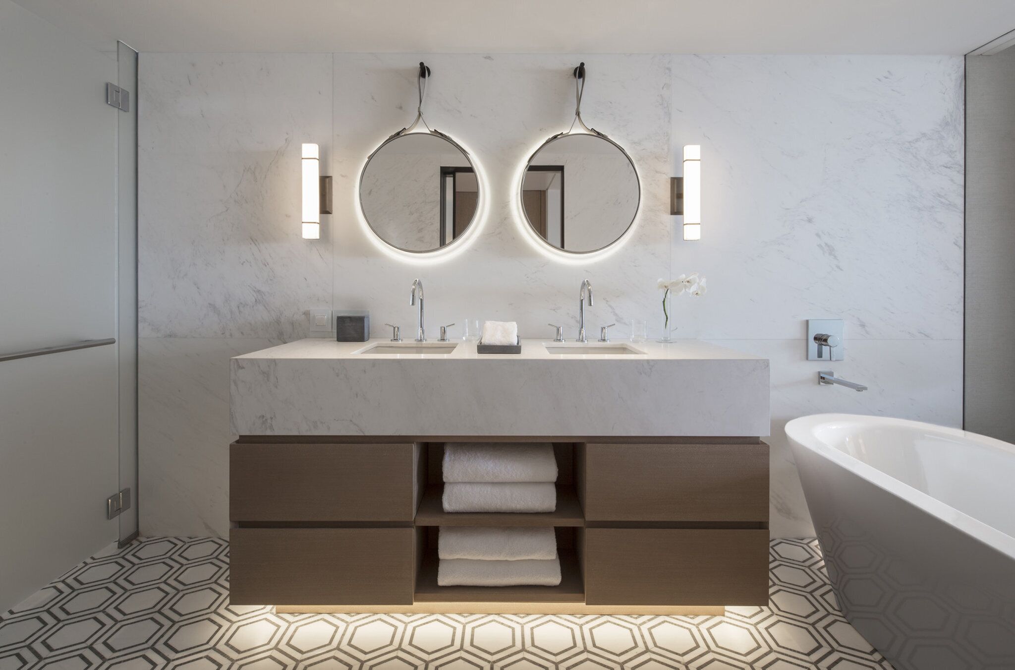 Un baño moderno con dos lavamanos, una bañera grande y un mueble de tocador con cajones de almacenamiento.