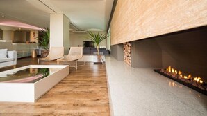 A modern living room with a fireplace, a glass coffee table, and a seating area with a chair and a sofa. - Langhetto Siena (Gramado)