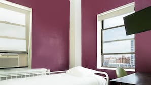 Une chambre avec un lit, un bureau et une fenêtre donnant sur la ville.