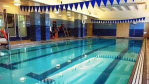 Une piscine intérieure avec des couloirs clairement délimités, un échelle et un poste de surveillance pour le sauveteur.