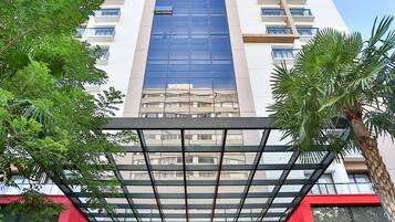 A modern building with a glass facade, a red entrance, and a staircase leading up to the entrance.