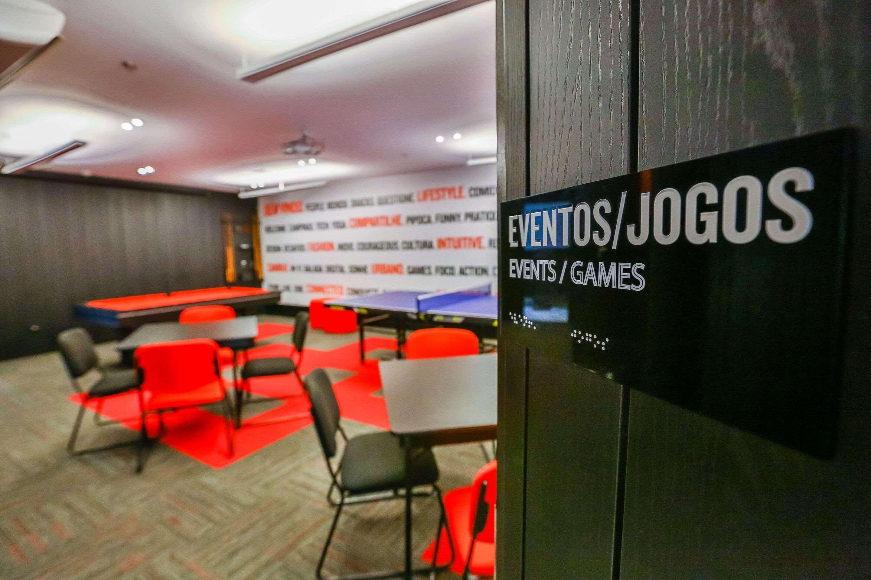 A conference room with tables and chairs, a banner with text, and a sign indicating events/games.
