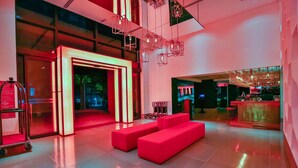 A modern lobby with a red sofa, a reception desk, and a large window. - Radisson RED Campinas (Campinas)