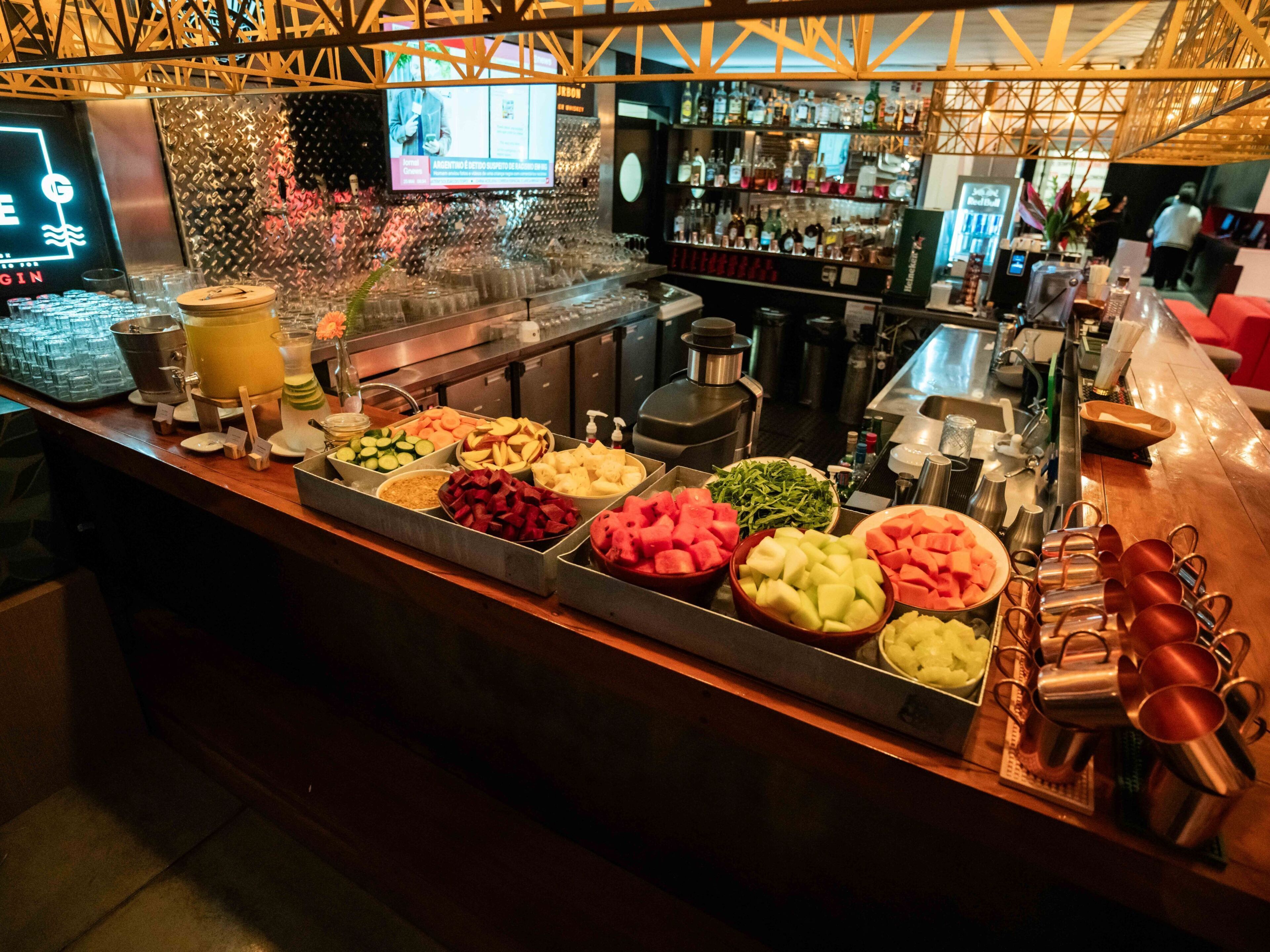 A buffet bar with various food items and a bar area with bottles and glasses.